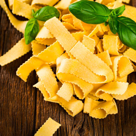 Ribbon Pasta Noodles Uncooked on Wooden Background. Selective focus.の写真素材