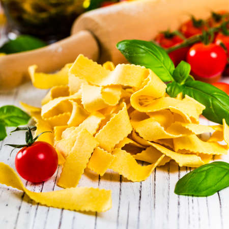 Ribbon Pasta Noodles Uncooked on White Wooden Background. Selective focus.の写真素材