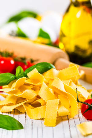 Ribbon Pasta Noodles Uncooked on White Wooden Background. Selective focus.の写真素材