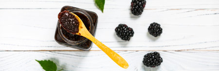 Jar of Blackberry Jam Preserves on White Wooden Background. Selective focus.