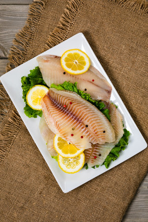 Whitefish Tilapia Fish Raw Fillet on Wooden Background. Selective focus.
