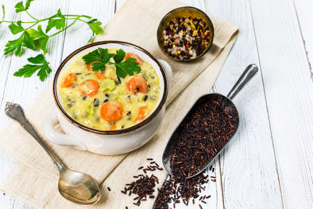 Creamy Wild Rice Soup on White Wooden Background. Homemade Fresh Creamy Soup with Chicken, Carrot, Vegetables and Wild Rice. Selective focus.の写真素材