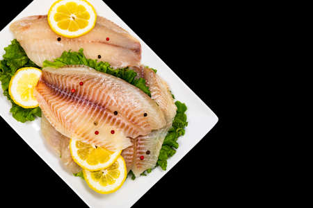 Whitefish Tilapia Fish Raw Fillet Isolated on Black Background. Selective focus.の写真素材
