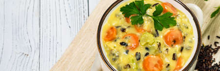 Creamy Wild Rice Soup on White Wooden Background. Homemade Fresh Creamy Soup with Chicken, Carrot, Vegetables and Wild Rice. Selective focus.の写真素材