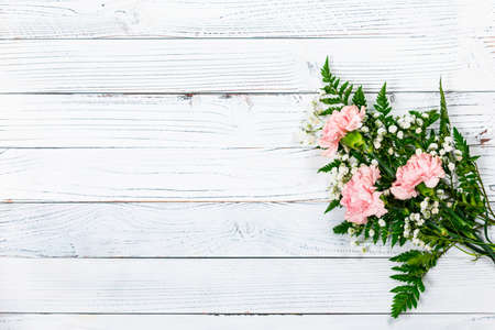 Top view of Carnation Flowers on White Vintage Wooden Background. Design concept for mothers day, wedding and valentines day with copy space. Selective focus.の写真素材