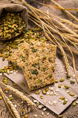 Multigrain Cereal Crunchy Squares Bars with Pumpkin Seeds on Wooden Background. Selective focus.の写真素材