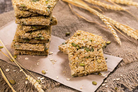 Multigrain Cereal Crunchy Squares Bars with Pumpkin Seeds on Wooden Background. Selective focus.の写真素材