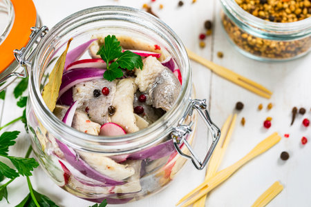 Pickled Marinated Herring with Spices, Radish and Red Onion on Wooden Background. Selective focus.