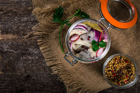 Pickled Marinated Herring with Spices, Radish and Red Onion on Wooden Background. Selective focus.の写真素材