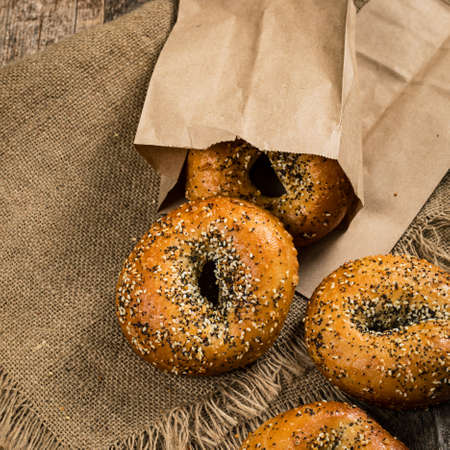 Freshly Baked Bagels Topped with Sesame Seeds, Poppyseeds, Garlic and Onion on Wooden Background. Selective focus.の写真素材