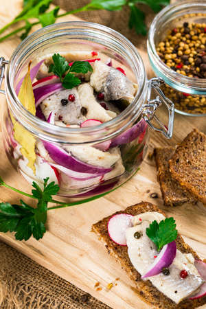 Pickled Marinated Herring with Spices, Radish and Red Onion on Wooden Background. Selective focus.の写真素材