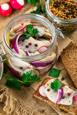 Pickled Marinated Herring with Spices, Radish and Red Onion on Wooden Background. Selective focus.の写真素材