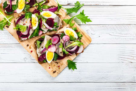 Pickled Marinated Herring and Beetroot Open Sandwich on Rye Bread. Traditional Danish Smorrebrod. Selective focus.