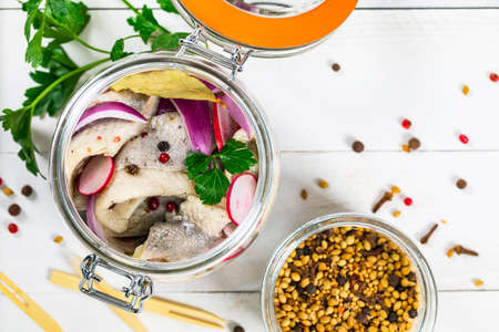 Pickled Marinated Herring with Spices, Radish and Red Onion on Wooden Background. Selective focus.の写真素材