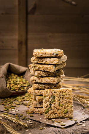 Multigrain Cereal Crunchy Squares Bars with Pumpkin Seeds Background. Healthy Bar Snack. Selective focus.の写真素材