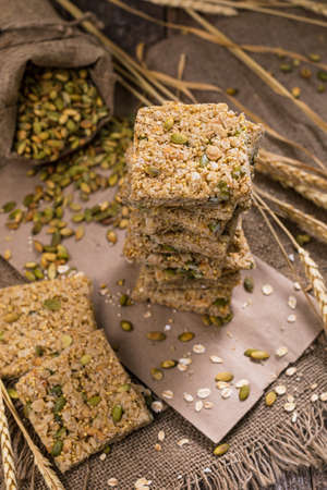 Multigrain Cereal Crunchy Squares Bars with Pumpkin Seeds Background. Healthy Bar Snack. Selective focus.の写真素材