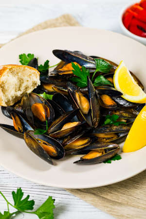 Delicious Seafood Mussels with Lemon and Parsley. Clams in the Shells on Wooden Background. Selective focus.の写真素材