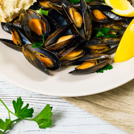 Delicious Seafood Mussels with Lemon and Parsley. Clams in the Shells on Wooden Background. Selective focus.の写真素材