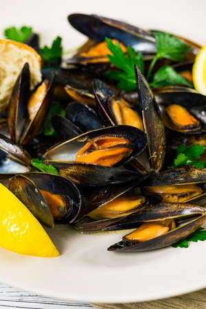Delicious Seafood Mussels with Lemon and Parsley. Clams in the Shells on Wooden Background. Selective focus.の写真素材