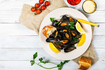 Delicious Seafood Mussels with Lemon and Parsley. Clams in the Shells on Wooden Background. Selective focus.