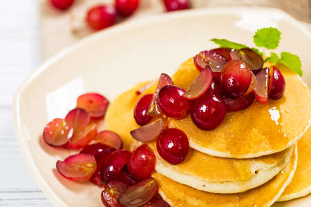 Healthy Homemade Classic American Pancakes with Sliced Red Grapes and Maple Syrup Close Up. Selective focus.の写真素材