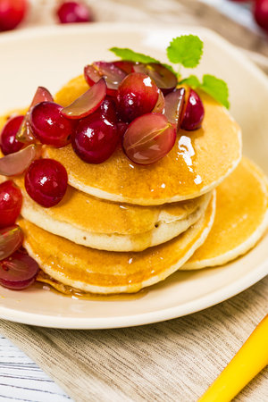 Healthy Homemade Classic American Pancakes with Sliced Red Grapes and Maple Syrup Close Up....