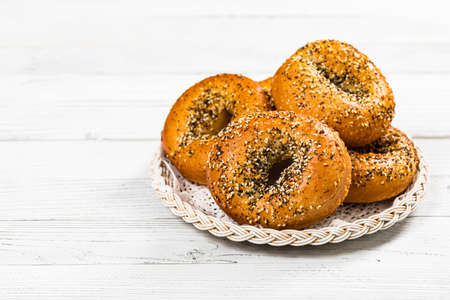 Freshly Baked Bagels Topped with Sesame Seeds, Poppyseeds, Garlic and Onion on Wooden Background. Selective focus.の写真素材