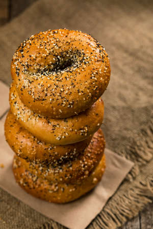 Freshly Baked Bagels Topped with Sesame Seeds, Poppyseeds, Garlic and Onion on Wooden Background. Selective focus.の写真素材