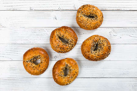 Freshly Baked Bagels Topped with Sesame Seeds, Poppyseeds, Garlic and Onion on Wooden Background. Selective focus.の写真素材