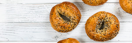 Freshly Baked Bagels Topped with Sesame Seeds, Poppyseeds, Garlic and Onion on Wooden Background. Selective focus.の写真素材