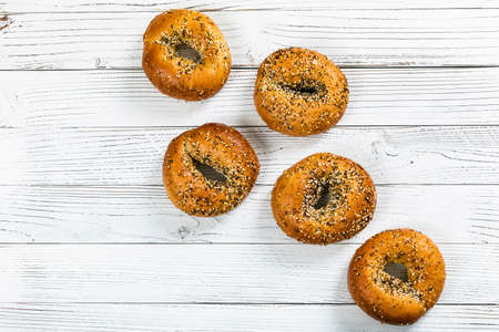 Freshly Baked Bagels Topped with Sesame Seeds, Poppyseeds, Garlic and Onion on Wooden Background. Selective focus.の写真素材