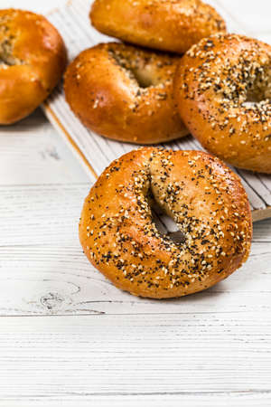 Freshly Baked Bagels Topped with Sesame Seeds, Poppyseeds, Garlic and Onion on Wooden Background. Selective focus.の写真素材