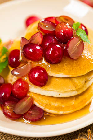 Stack of Pancakes with Sliced Red Grapes and Maple Syrup. Selective focus.の写真素材