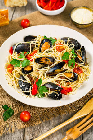Seafood Pasta Spaghetti with Mussels and Tomatoes on Wooden Background. Italian Cuisine. Selective focus.の写真素材