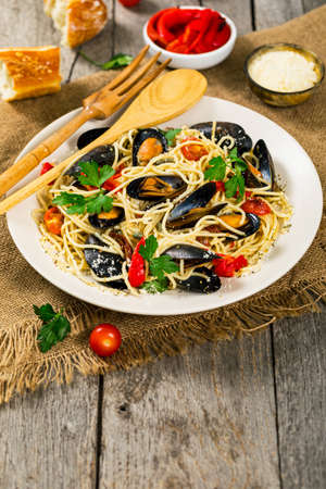 Seafood Pasta Spaghetti with Mussels and Tomatoes on Wooden Background. Italian Cuisine. Selective focus.の写真素材