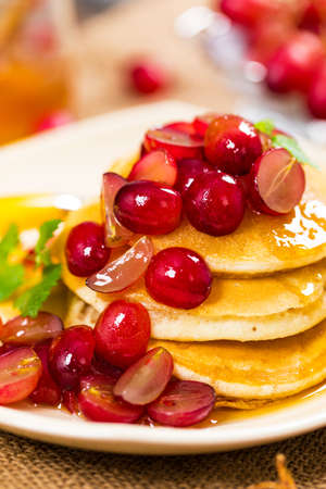 Stack of Pancakes with Sliced Red Grapes and Maple Syrup for breakfast. Selective focus.の写真素材