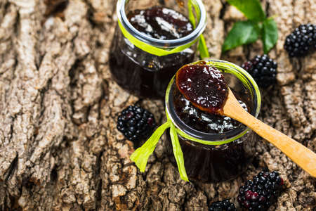 Jar of Blackberry Jam Preserves on Old Wooden Background. Selective focus.の写真素材