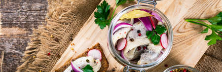 Pickled Marinated Herring with Spices, Radish and Red Onion on Wooden Background. Selective focus.の写真素材