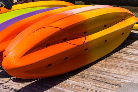Closeup View of Many Colorful Kayaks Drying in Sun on a Pier. Colored Canoes are Waiting for Tourists. Selective focus.の写真素材