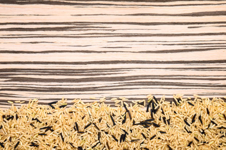 brown and wild mixed rice framed on a zebrano wooden background