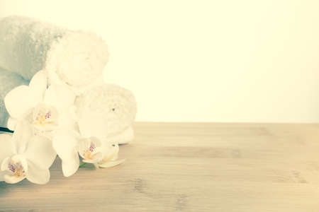 Spa set of white orchid flower and rolled  towel on wood background, vintage style, closeup  の写真素材