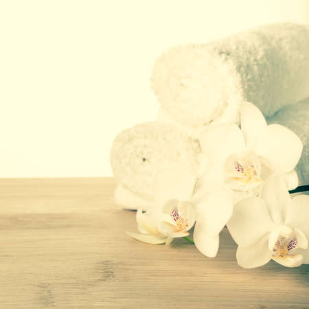 Spa set of white orchid flower and rolled  towel on wood background, vintage style, closeup  の写真素材