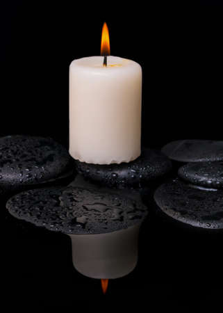 spa concept of candle on zen stones with drop in reflection water, closeupの写真素材