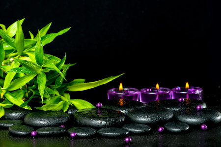 spa concept of zen basalt stones with drops, lilac candles, beads and bamboo, closeupの写真素材