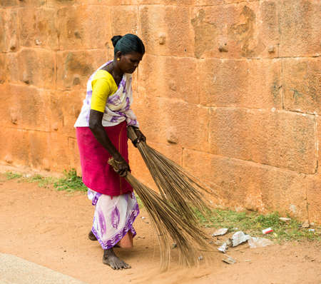 THANJAVUR, INDIA - FEBRUARY 14: An unidentified Indian woman in national dress carries sweeping the two brooms at Brihadishwara Temple. India, Tamil Nadu, Thanjavur. February 14, 2013.のeditorial素材