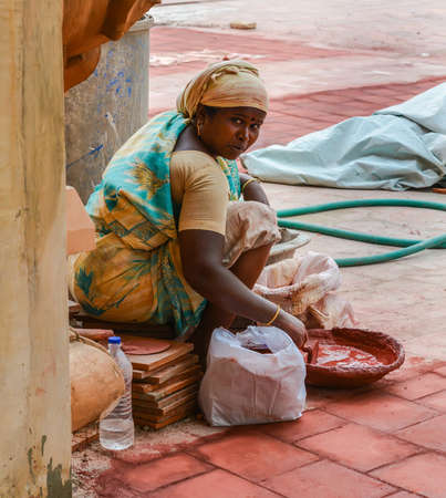 THANJAVOUR, INDIA - FEBRUARY 14: An unidentified Indian woman  in national costumes stirs the red dye in  bowl. India, Tamil Nadu, Thanjavour. February 14, 2013のeditorial素材