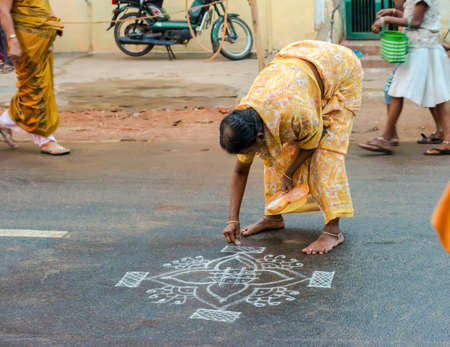 THANJAVOUR, INDIA - FEBRUARY 14: An unidentified woman paints ornaments rice flour on the asphalt road. India, Tamil Nadu, Thanjavour. February 14, 2013のeditorial素材
