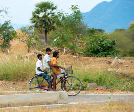 TRICHY, INDIA - FEBRUARY 15: An unidentified three teenage boy riding a bike on a rural road. India, Tamil Nadu, near Trichy. February 15, 2013のeditorial素材