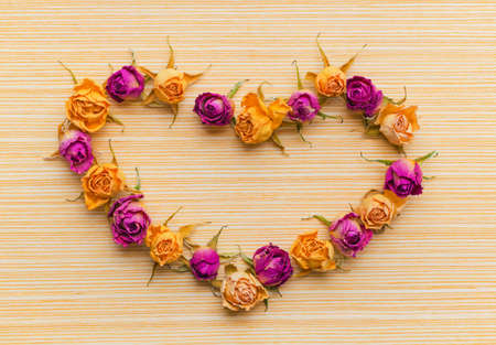 Beautiful greeting card of Valentine with dried pink and yellow roses on wooden backgroundの写真素材