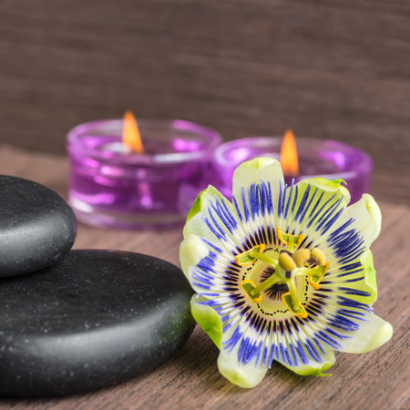 beautiful spa concept of passiflora flower, black zen stones and candles  on wooden background, closeupの写真素材